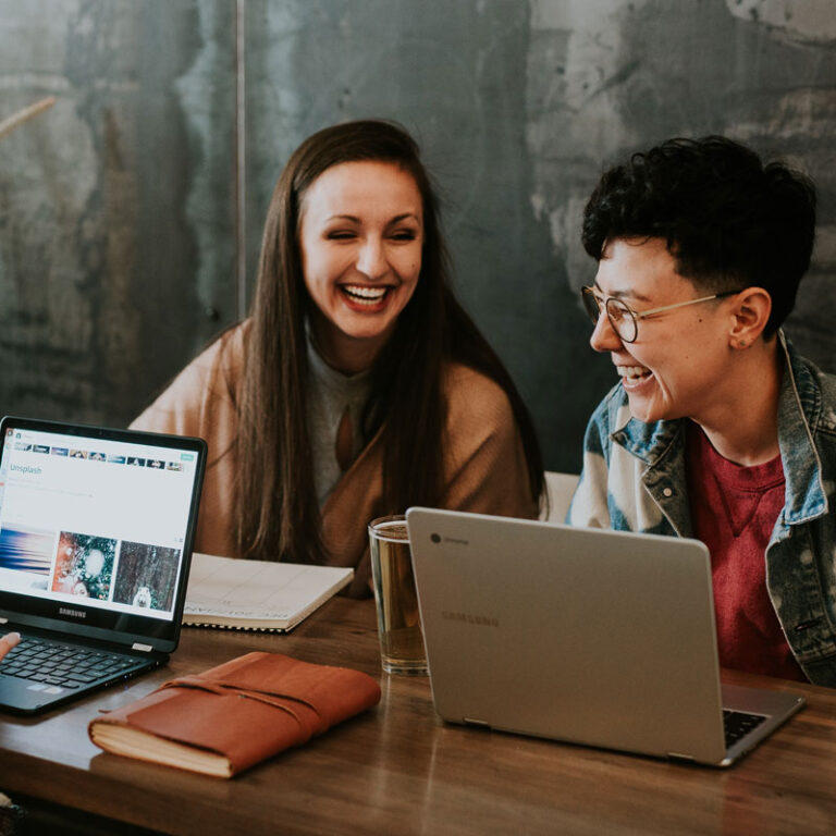 Colleagues talking together at a shared desk in a bright office